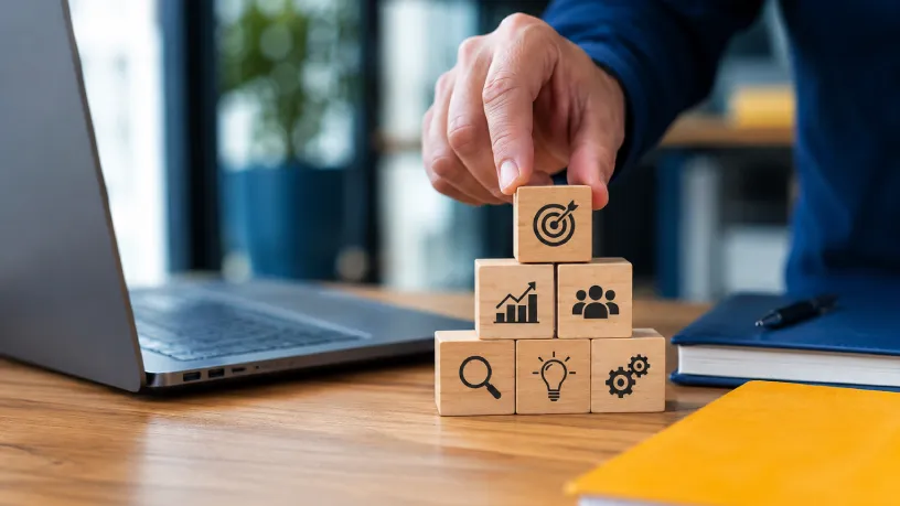 Profissional organizando blocos com ícones de estratégia e crescimento ao lado de um notebook em ambiente corporativo moderno, representando fortalecimento de marca, autoridade digital, reputação online e crescimento empresarial.