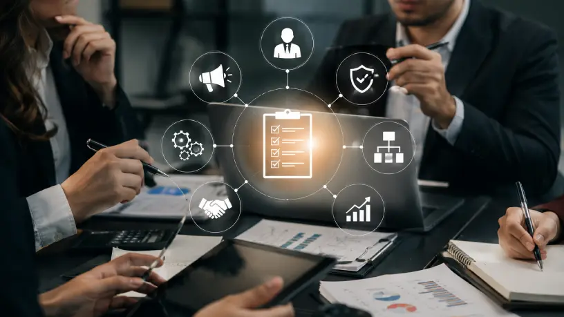 Profissionais reunidos em planejamento estratégico com ícones de processos, comunicação e organização, sob uma mesa com cadernos e papéis, ilustrando a importância de um plano de gestão de crise para empresas.